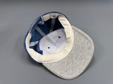 grey and blue baseball cap with a white visor on a gray surface