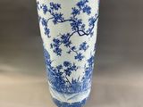 tall blue and white vase with trees and flowers on it
