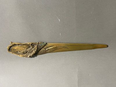 une cuillère en or ornée d'un oiseau, posée sur une table