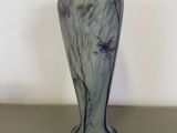 a blue vase sitting on a table with a white wall in the background