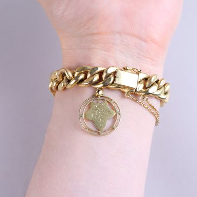 gold bracelet with a heart charm and a chain on a woman ' s wrist