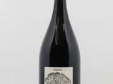 the bottle of red wine is sitting on a white surface