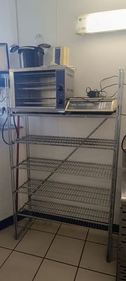 une photo d'une cuisine avec un micro-ondes et une étagère