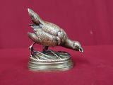 une statue en bronze représentant un oiseau perché sur une table
