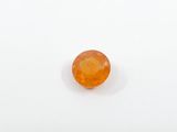an orange sapphire stone sitting on top of a white surface