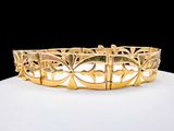 une photo d'un bracelet en or posé sur une surface blanche