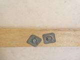 two metal studs on a wooden shelf next to a white wall