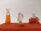 three bottles of perfume sitting on an orange cloth