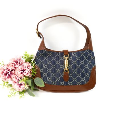 blue and brown guccissi handbag with flowers on a white background