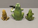three figurines of frogs and a frog on a table