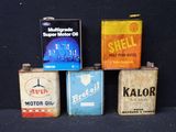 Quatre bidons d'huile de moteur vintage sont alignés sur une surface noire
