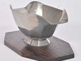 a silver bowl on a wooden stand on a white background