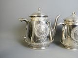 pair of antique silver teapots with ornate designs on them