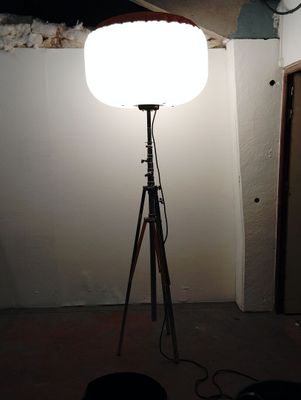 une lampe posée sur un trépied dans une pièce
