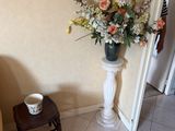 a vase of flowers on a pedestal in the corner of a room