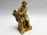 statue of a man sitting on a chair holding a book