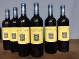 six bottles of red wine are lined up on a table
