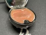 a small silver box with a pink substance inside of it