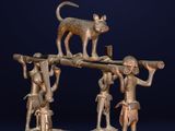 a bronze figurine of a cat on top of a group of people
