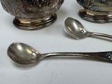 three silver spoons and a silver bowl on a table