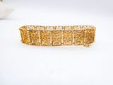 a close up of a gold bracelet on a white surface