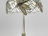 une lampe posée sur une table, dont l'abat-jour représente une libellule