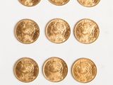 un gros plan sur plusieurs pièces d'or posées sur une surface blanche