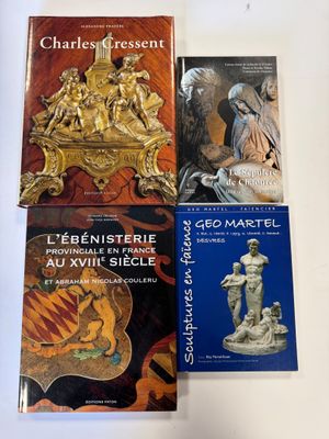 trois livres posés sur une table blanche, avec une horloge et une statue