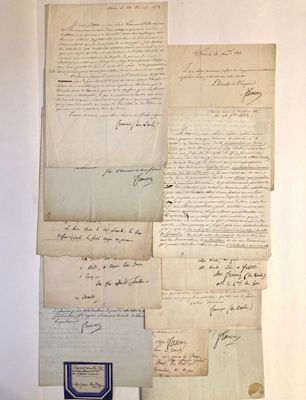 quelques vieux papiers sont posés sur une table, à côté d'un stylo et d'encre