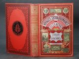 an old book with a red cover sitting on top of a table