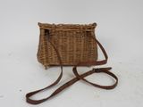 an old wicker purse with a leather strap on a white background