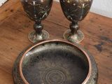 two vases and a bowl sitting on a wooden table