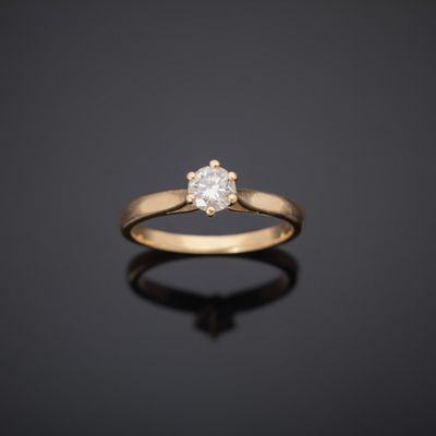 a single stone diamond ring on a black surface