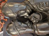 a bronze statue of a man sleeping on a chair
