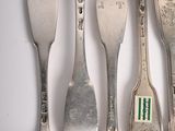 several forks and spoons are lined up on a white surface