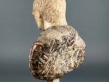 a marble bust of a man with long hair on a pedestal