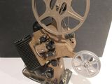 un vieux projecteur de cinéma posé sur une table à côté d'un appareil photo