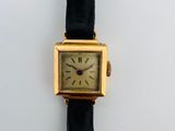 une photo d'une montre plaquée or avec un bracelet en cuir noir