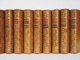 six vieux livres sont alignés sur une surface blanche