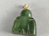 a close up of a green jade pendant on a white surface