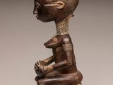 a wooden statue of a man sitting on a stool