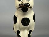 une figurine de chat noir et blanc posée sur une surface grise