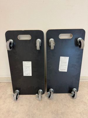 une paire de sacs de voyage en plastique noir à roulettes posés sur un sol recouvert de moquette