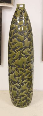 a large green vase sitting on a table with pictures on the wall behind it