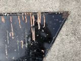 a black triangle with rust on it sitting on the sidewalk