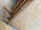 a cat that is sitting on the floor next to a pile of pipes