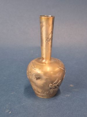 un petit vase en or posé sur un fond bleu