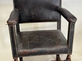 un vieux fauteuil en cuir avec des pieds en bois et une assise en cuir