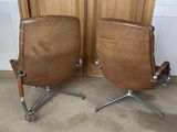 pair of brown leather office chairs sitting in front of a wooden door