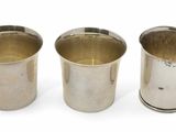 trois tasses en argent posées l'une à côté de l'autre sur une surface blanche